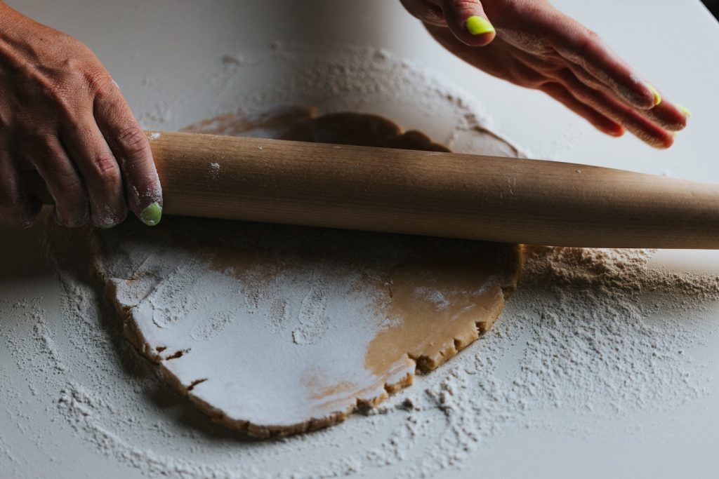 person holding brown wooden rolling pin